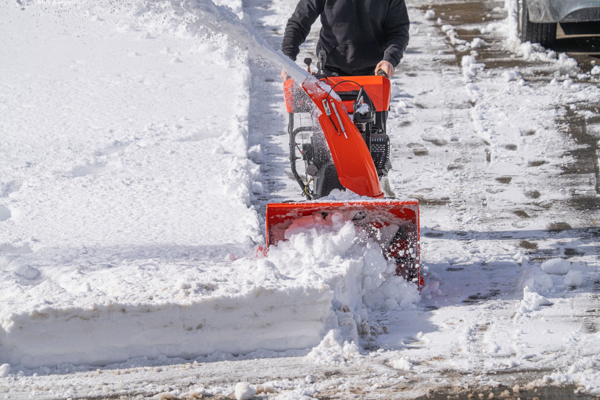 man removing snow on the driveway of the house by snow blower